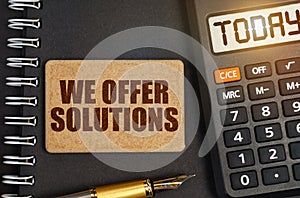 On the notebook there is a calculator with the inscription Today and a sign with the inscription - We Offer Solutions
