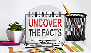 Notebook with Tools and Notes with text UNCOVER THE FACTS business concept