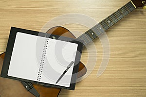 Guitar, Notebook on Wood Background.