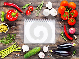 Notebook with vegetables and herbs on wooden table background