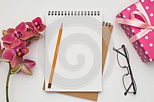 Notebook on white table with gift and pencil