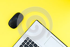 A notebook with a wireless mouse on a yellow background and a place for text. Flat Lay. Top view