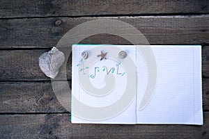 Notebook on a wooden background with seashells
