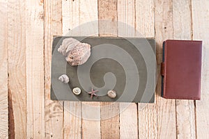 Notebook on a wooden background with seashells.