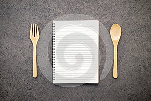 Notebook with wooden spoon set up on dark stone background
