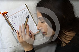 Notebook with the word Dreams written, next to a sleeping woman photo