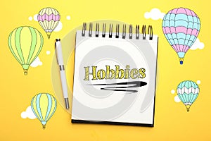 Notebook with word Hobbies and pen on background, top view