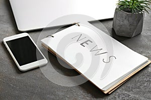 Notebook with word NEWS and phone on table