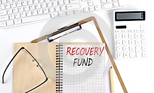 Notebook with the word RECOVERT FUND with keyboard and calculator on the white background