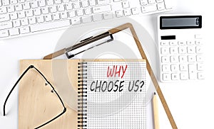 Notebook with the word WHY CHOOSE US with keyboard and calculator on the white background