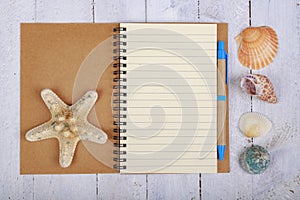 Notebook for writing your vacation memories. A blank sheet and seashells from the seaside