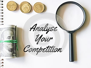 Notebook written analyse your competition with coins,fake money and magnifying glass.