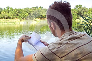 Notebook of a young man, a man close to the lake, painting landscape in Notepad. Summer Sunny day. to turn the page photo