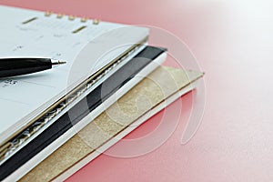 Notebooks, calendar and pen on pink background
