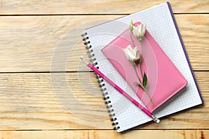notebooks and pencils beautiful eustoma flowers on a natural wooden table. top view.