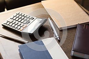 Notebooks, pens and calculator on table