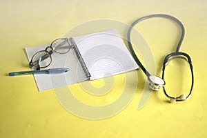 Notebooks and pens placed on a yellow background with medical headsets Working concepts