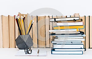 Notebooks piles, stack of books education back to school background, textbooks, glasses and pencils in concrete holder with copy