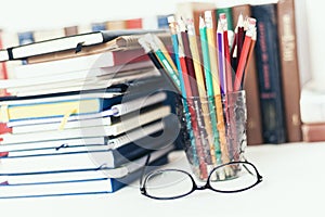 Notebooks piles, stack of books education back to school background, textbooks, glasses and pencils in holder with copy space for