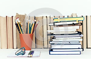 Notebooks piles, stack of books education back to school background, textbooks, glasses and pencils in holder with copy space for
