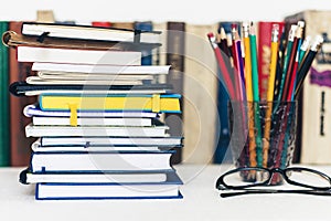 Notebooks piles, stack of books education back to school background, textbooks, glasses and pencils in holder with copy space for