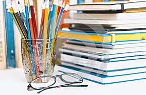 Notebooks piles, stack of books education back to school background, textbooks, glasses and pencils in plastic holder with copy