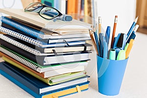 Notebooks piles, stack of books education back to school background, textbooks, glasses and pencils in plastic holder with copy