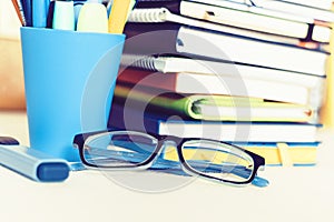 Notebooks piles, stack of books education back to school background, textbooks, glasses and pencils in plastic holder with copy