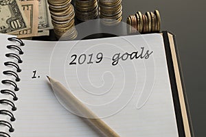 Notepad with 2019 goals text, pencil, money background