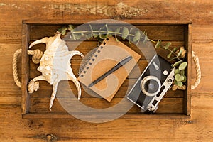 Notepad, black pen, vintage film camera and large seashell in a