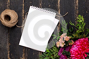 Notepad with a bouquet of flowers on a dark vintage wooden background