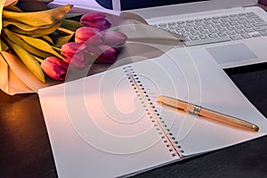 Notepad with bouquet of tulips on dark background
