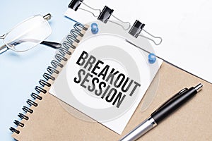 Notepad with breakout session text on the office table with glasses, notepad and paper with clips