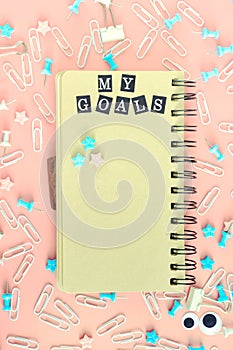 Notepad with brown pages, on springs. The inscription My Goals. The stationery is in disarray. Staples, paper clips and