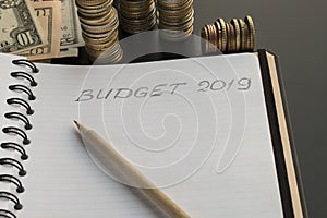 Notepad with Budget 2019 text, pencil and money background