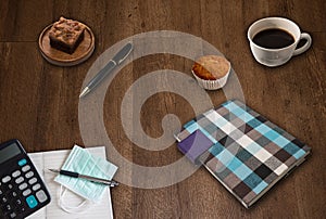 Notepad, Calculator, Pen, Black Coffee, Toffees, Cupcakes and Medical Masks on Wood