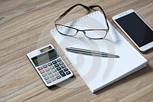 Notepad, calculator, smartphone, glasses and sliver ballpen