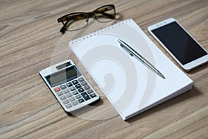 Notepad, calculator, smartphone, glasses and sliver ballpen