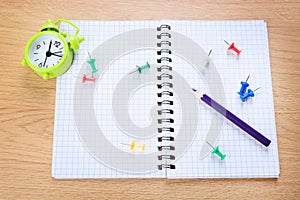 Notepad with colored pen, paper,clips and alarm clock on a table