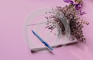 Notepad with a Cup of tea, a pen and a bouquet of lavender on a purple background, side view, space for text, tinting in a purple