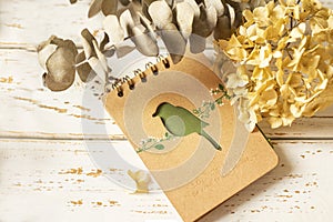 Notepad and dried flowers on a white wooden background