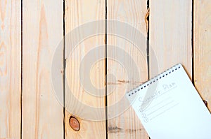 Notepad with entries for summer plans on a wooden background
