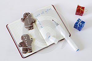 Notepad with gift list template, gingerbread men and gift boxes on white. Concept of congratulations on the new year and Christmas