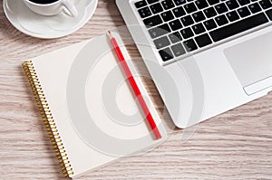 Notepad, laptop and coffee cup on wood table