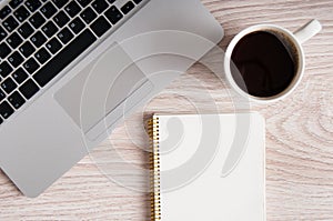 Notepad, laptop and coffee cup on wood table