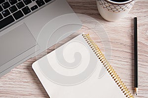 Notepad, laptop and coffee cup on wood table