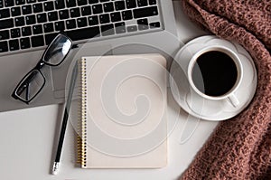 Notepad, laptop and coffee cup on wood table