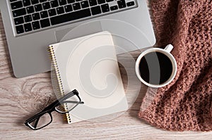 Notepad, laptop and coffee cup on wood table