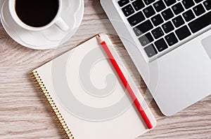 Notepad, laptop and coffee cup on wood table
