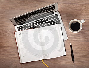 Notepad, laptop and coffee cup on wood table